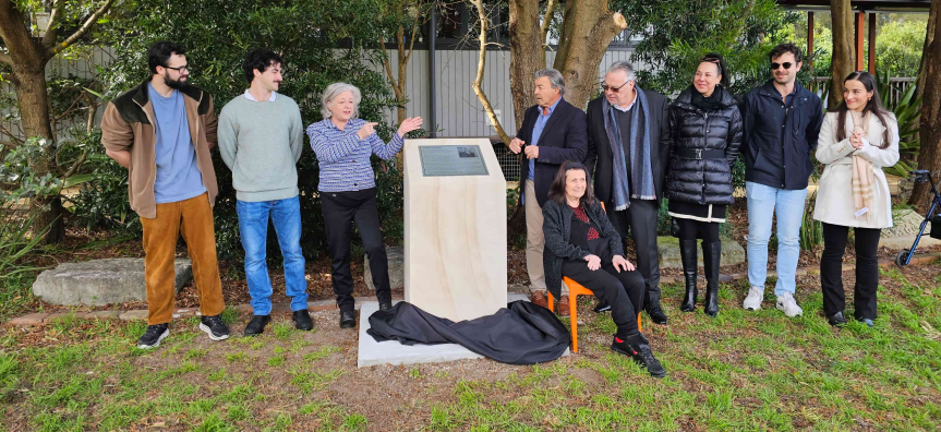 people standing next to sandstone plinth with plaque