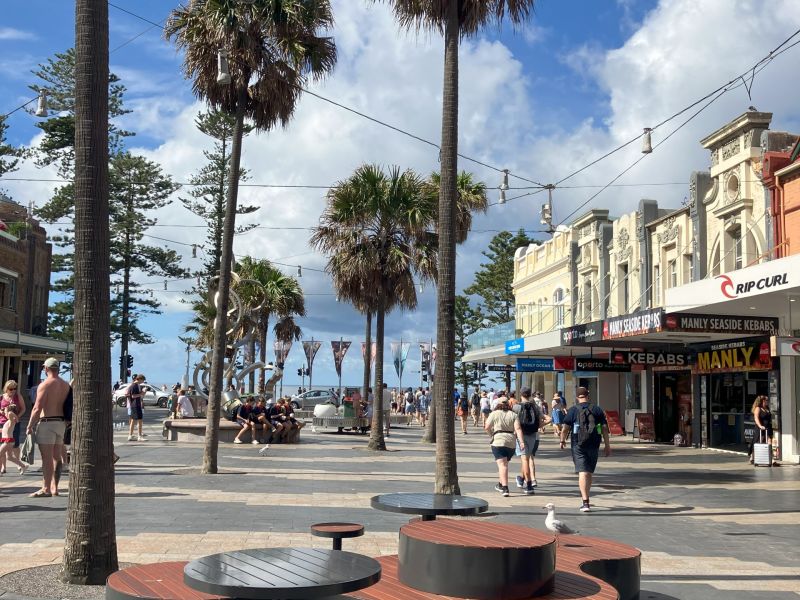 furniture in public space, palm trees and shops in background